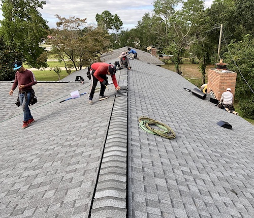 workers installing ridge cap on shingle roof in leland nc